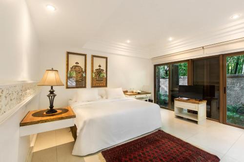 a white bedroom with a bed and a television at Villa Pantai Karang in Sanur