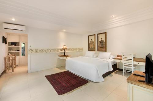 a white bedroom with a bed and a desk at Villa Pantai Karang in Sanur