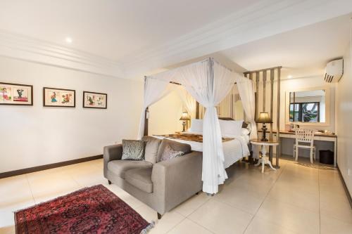 a bedroom with a bed and a couch and a bed at Villa Pantai Karang in Sanur