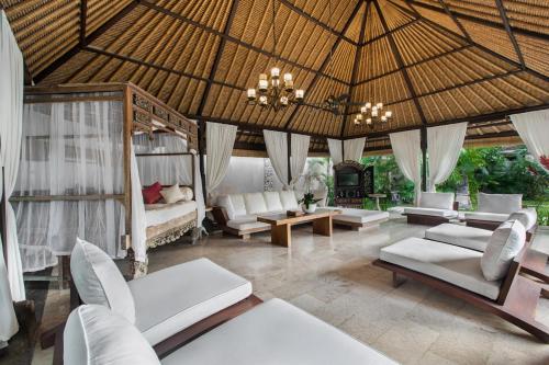 a living room with white furniture and a chandelier at Villa Pantai Karang in Sanur