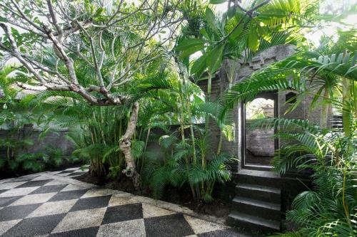 a courtyard with a tree and a checkered floor at Villa Pantai Karang in Sanur