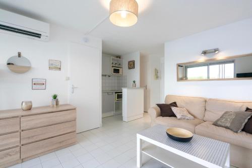 een woonkamer met een bank en een tafel bij Appart 6 pers vue mer-piscine-parking-clim-wifi in Cap d'Agde