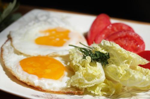 a plate of eggs and lettuce and fruit on a table at Snow Leopard Hostel in Karakol