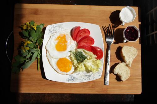a plate of eggs and tomatoes and bread on a table at Snow Leopard Hostel in Karakol