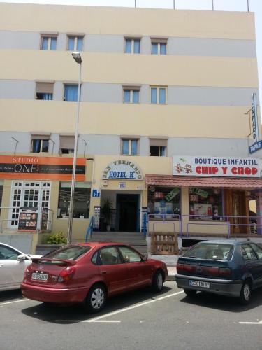 two cars parked in a parking lot in front of a building at Hostal Casa de Huéspedes San Fernando - Adults Only in Playa del Ingles