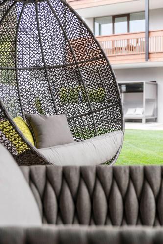 a wicker swing with a pillow in a yard at Hotel Clara in Bressanone