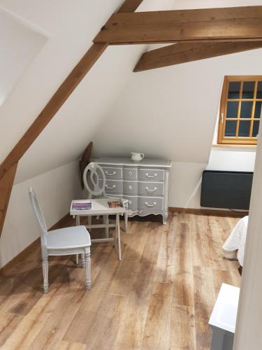 Cette chambre mansardée comprend une commode et une chaise. dans l'établissement la ferme chevalier, à Équemauville