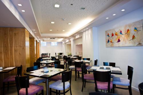 a dining room with tables and chairs and a painting on the wall at Montefiore Hotel By Smart Hotels in Jerusalem