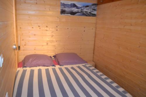 Saint-Julien-en-ChampsaurにあるPetit appartement en montagneの木製の壁のベッド1台が備わる小さな客室です。