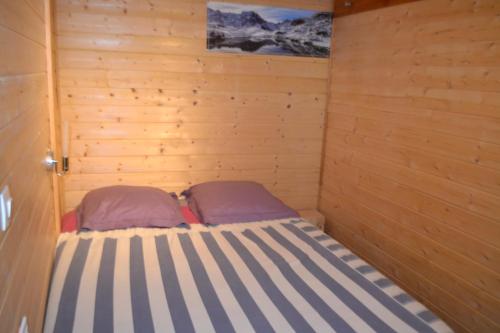 a small room with a bed in a wooden wall at Petit appartement en montagne in Saint-Julien-en-Champsaur