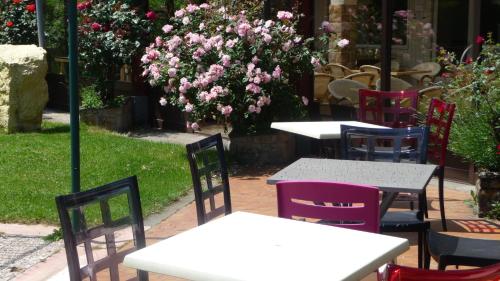 a group of tables and chairs with pink flowers at Logis La Rose Des Vents in Volvic