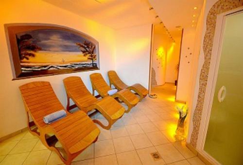a waiting room with orange chairs and a painting on the wall at Hotel Nigritella in Selva di Cadore