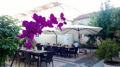 un patio con mesas, sombrillas y flores púrpuras en Abas Ristorante Pizzeria Affittacamere, en Ales