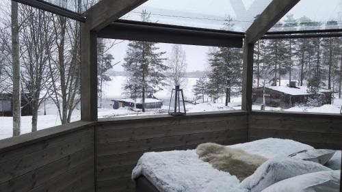 a room with a window with snow on a bed at Revontuli Resort Glass Igloos in Hankasalmi