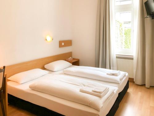 1 dormitorio con 2 camas en una habitación con ventana en Hotel Moon, en Düsseldorf