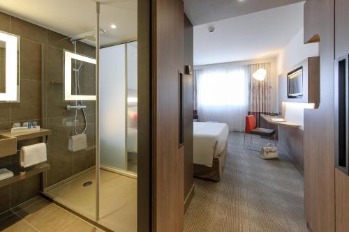 a hotel room with a bed and a bathroom at Novotel Lugano Paradiso in Lugano