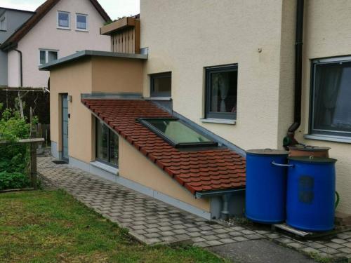 a house with a red roof and two trash cans at Einzelnwohnung mit eigenem Eingang in Weingarten