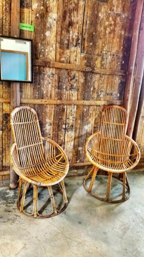 two wicker chairs sitting next to a wall at Borneo Tribal Village (BTV) in Pelaman Sodoh