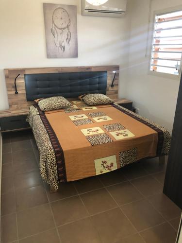 1 dormitorio con 1 cama con cabecero de madera en Appartement résidentiel, en Le Moule