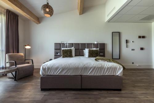 a bedroom with a large bed and a chair at Fruitpark Hotel & Spa in Ochten