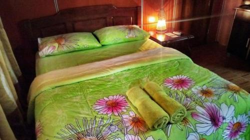 a bed with a green comforter with flowers on it at Borneo Tribal Village (BTV) in Pelaman Sodoh