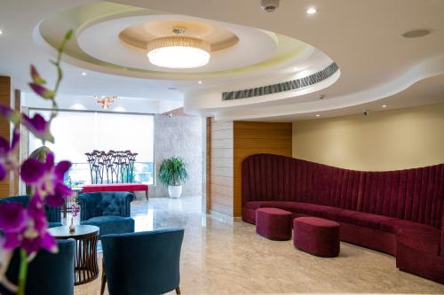 a lobby with a waiting room with red furniture and purple flowers at Regenta Central Cassia Zirakpur Chandigarh in Chandīgarh