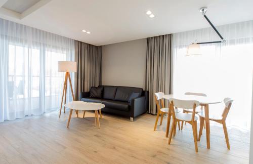 a living room with a couch and a table and chairs at Apartamenty Sun Seasons 24 - Gardenia in Dziwnów