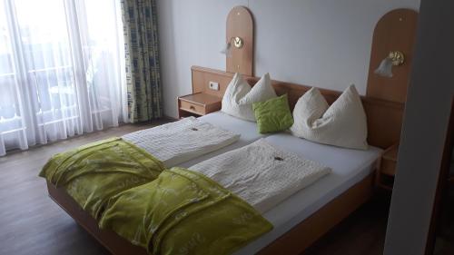 a bed with green and white sheets and pillows at Pension Untergasser in Weissensee