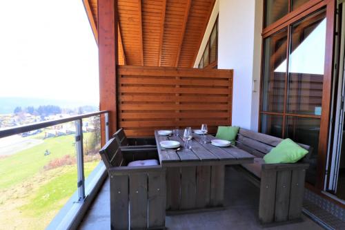 a wooden table on the balcony of a house at UplandParcs Residence Astenberg in Winterberg