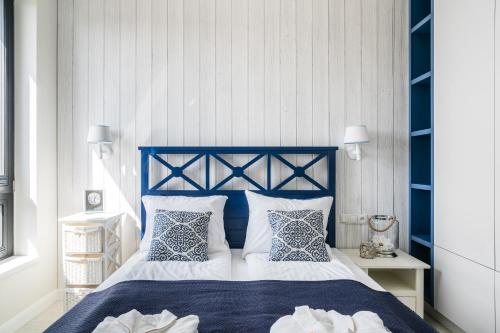 Un dormitorio con una cama azul y blanca con almohadas en Lion Apartments - Blue Marina Premium Apartment Okrzei 21, en Sopot