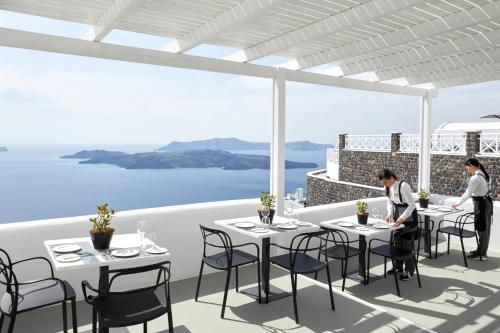 a rendering of a restaurant with tables and chairs at Petit Palace Suites in Fira