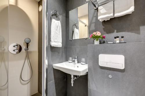 La salle de bains est pourvue d'un lavabo et d'une douche. dans l'établissement Hôtel Alexandrine Opera, à Paris