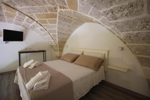 - une chambre avec un lit et un mur en pierre dans l'établissement VILLA ROSA, à Torre Suda