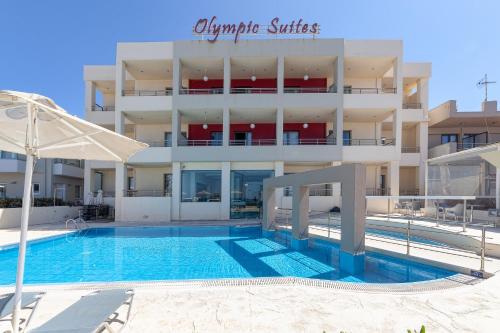 a hotel with a swimming pool in front of a building at Olympic Suites in Rethymno