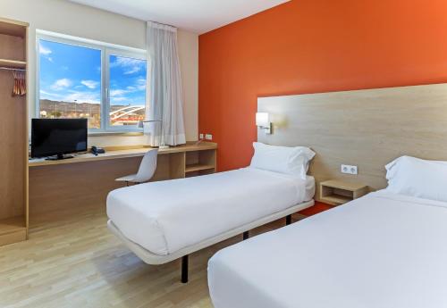 a hotel room with two beds and a television at B&B HOTEL Madrid Las Rozas in Las Rozas de Madrid