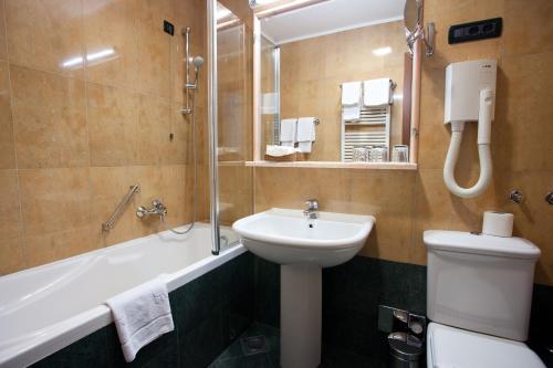 a bathroom with a sink and a tub and a toilet at Hotel Globo in Split