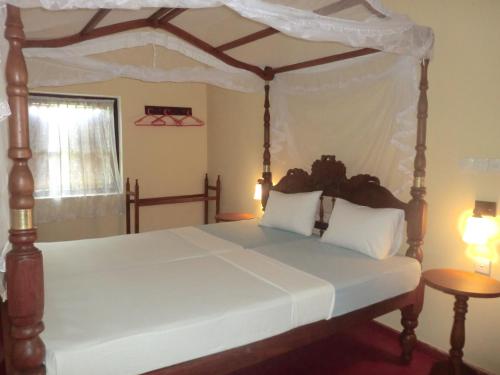 1 dormitorio con cama con dosel y sábanas blancas en Top of the Hill Guesthouse, en Weligama