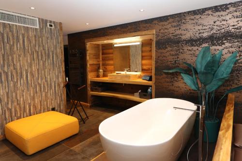 een badkamer met een wit bad en een wastafel bij Chambres d'hôtes Le Repère des Anges et SPA in Larnod