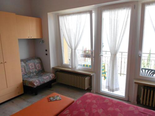 a living room with two large windows and a chair at Hotel Casa Gagliardi in Brenzone sul Garda