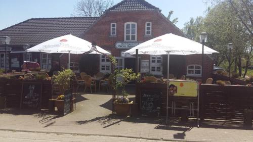 two white umbrellas in front of a building at H5 Haus Schwalbennest Kaminofen WLAN in Butjadingen