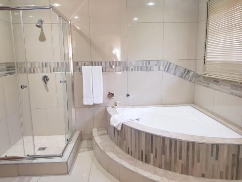 a bathroom with a tub and a glass shower at Angel Guest House in Lydenburg