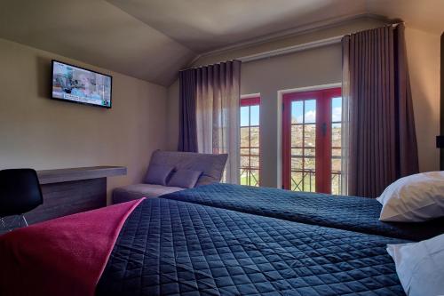 a bedroom with a bed and a chair and a television at Alojamento Local - Miradouro do Castelo in Castro Laboreiro