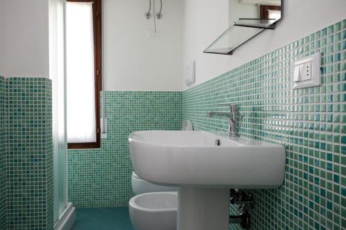 Baño de azulejos verdes con lavabo y aseo en Residenza Jennifer, en Lido di Jesolo