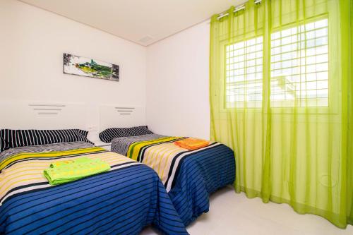 - 2 lits dans une chambre avec des rideaux verts dans l'établissement Espanatour VIRGINIA, à Torrevieja