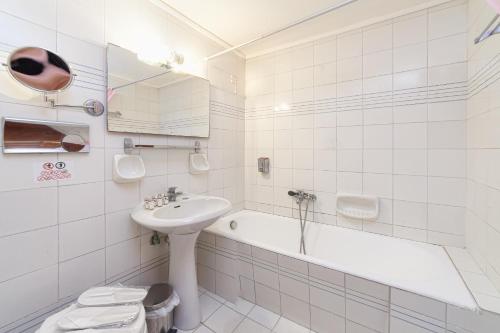 a white bathroom with a sink and a bath tub at Olympic Suites in Rethymno Town