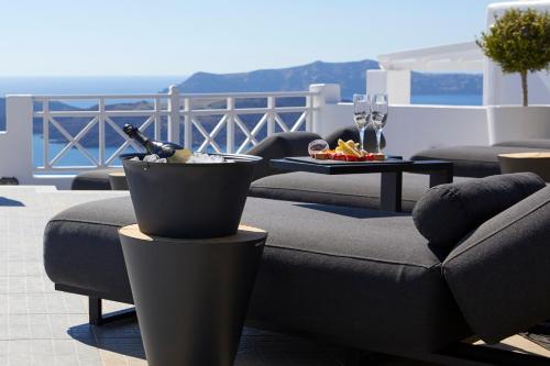 a patio with a table with wine glasses and a couch at Petit Palace Suites in Fira