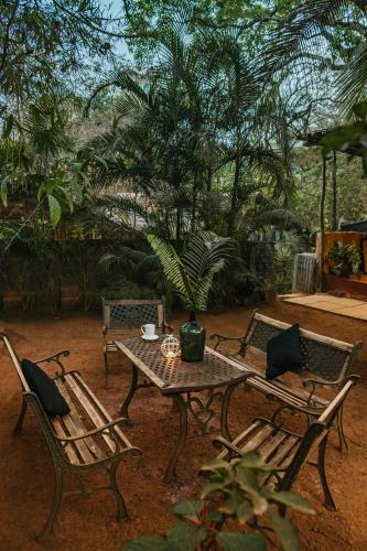 a table and two chairs and a table with a vase at Namaste Jungle - A Boutique Homestay in Assagao