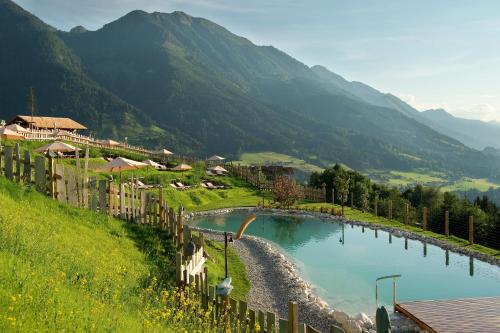 a large pool of water with mountains in the background at Chaletdorf BERGHERZ in Sankt Johann im Pongau