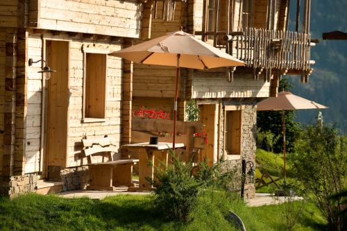 a patio with a table and an umbrella in front of a building at Chaletdorf BERGHERZ in Sankt Johann im Pongau