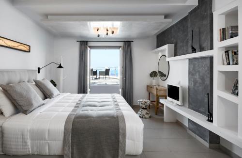 a white bedroom with a large bed and a television at Petit Palace Suites in Fira